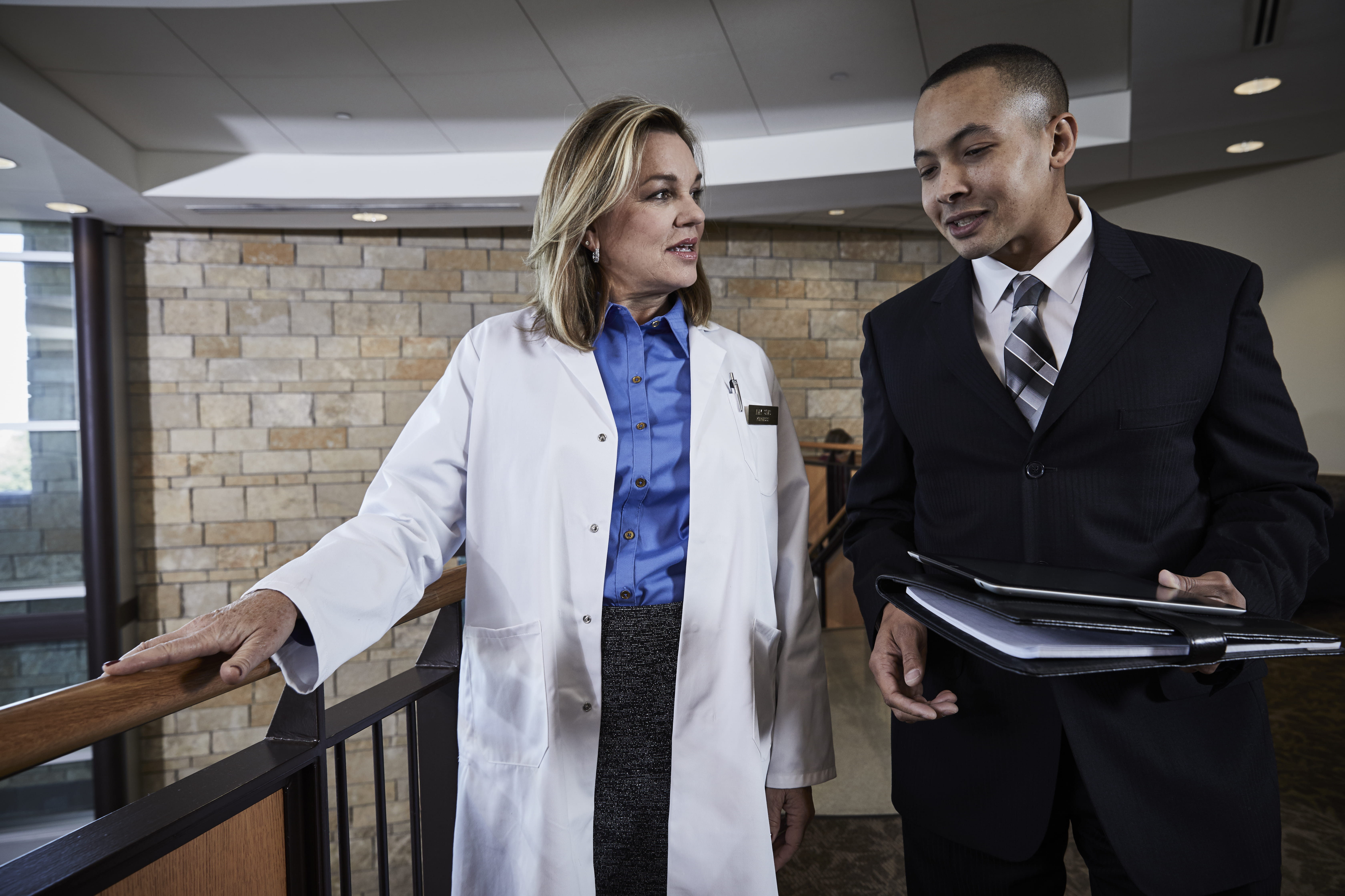 Female doctor speaks with male rep in hallway