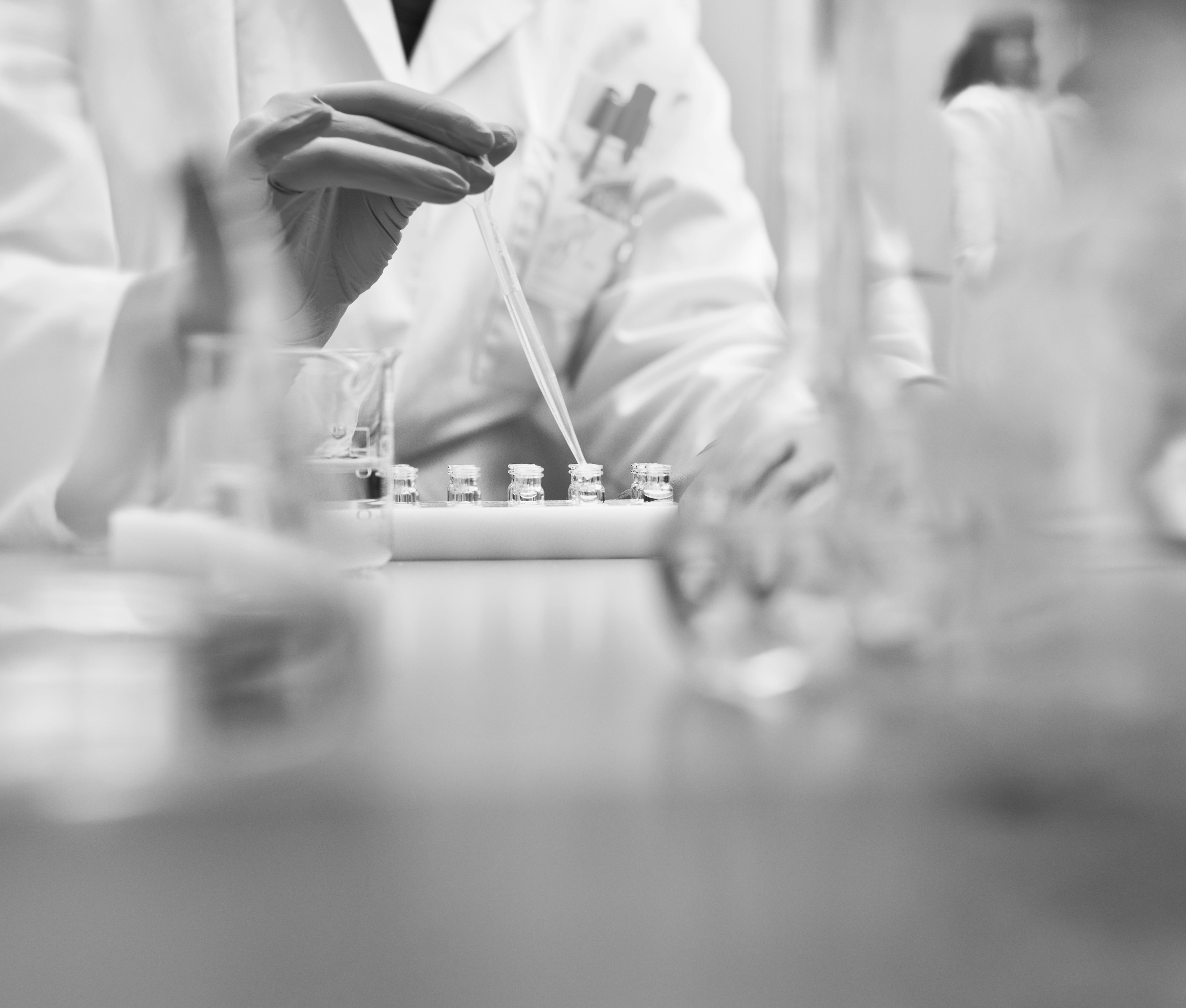 Lab technician conducting testing with vials and dropper